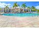 Community pool with clear blue water, palm trees, poolside seating and covered clubhouse at 8413 Placida Rd # 205, Placida, FL 33946
