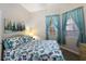 Cozy bedroom with a colorful comforter, two sunny windows with curtains, and neutral-colored walls at 8500 Amberjack Cir # 102, Englewood, FL 34224