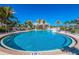 A large community pool is surrounded by lounge chairs and mature palm trees, all under a clear blue sky at 8500 Amberjack Cir # 102, Englewood, FL 34224