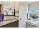 Modern bathroom with tiled walls, dual sink vanity, and glass block window, offers a serene spa-like experience at 9574 Arsipe Cir, Port Charlotte, FL 33981