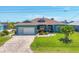 Inviting single-story home with a lush green lawn, paver driveway, and an American flag at 9574 Arsipe Cir, Port Charlotte, FL 33981