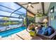 Relaxing screened lanai with a covered seating area, pool, canal view, and lush tropical landscaping at 9574 Arsipe Cir, Port Charlotte, FL 33981