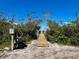 Private dock boardwalk surrounded by tropical vegetation, leading to serene waterfront property at 9580 Almirate Ct, Placida, FL 33946