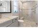 The neutral-toned bathroom features a glass shower, updated vanity, and stone flooring at 10115 Long Branch St, Port Charlotte, FL 33981