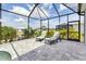 Relaxing pool patio enclosed with black framing, featuring two lounge chairs and tropical foliage at 10115 Long Branch St, Port Charlotte, FL 33981