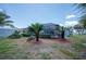 Landscaped backyard featuring a screened lanai, palm trees, and manicured shrubs offering a private oasis at 10182 Charlemont Ave, Englewood, FL 34224