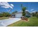 Exterior view of the house with a spacious driveway, American flag, and lush, green lawn at 10182 Charlemont Ave, Englewood, FL 34224