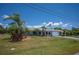 Landscaped home exterior with palm trees, decorative flower beds, and an American flag flying at 10182 Charlemont Ave, Englewood, FL 34224