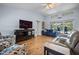 Spacious living room with wood flooring, a ceiling fan, and large windows providing natural light at 10182 Charlemont Ave, Englewood, FL 34224