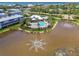 Picturesque aerial view showcasing a community pool, buildings, and tranquil lakes with fountain features at 10411 Coral Landings Ln # 85, Placida, FL 33946
