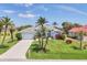 Charming single-Gathering home featuring a manicured lawn, mature palm trees, and a concrete driveway at 11 Amberjack Ln, Placida, FL 33946