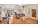 Warm living room featuring hardwood floors, leather sofas, adjacent dining area, and large sliding glass doors at 11008 Waterford Ave, Englewood, FL 34224