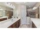 Bathroom with double sink vanity, large mirrors, tiled walk-in shower, and light fixtures at 11125 Mcdermott Ct, Englewood, FL 34223