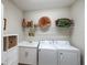 Well-lit laundry room with side-by-side washer and dryer and utility sink at 11125 Mcdermott Ct, Englewood, FL 34223