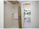 Neutral tiled shower with a palm-themed shower curtain, leading to a sunroom with outdoor views and a charming bistro set at 113 Annapolis Ln, Rotonda West, FL 33947