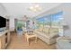 Bright living room with a comfy sofa, glass table, television, and sliding glass doors to the outdoor patio at 113 Annapolis Ln, Rotonda West, FL 33947