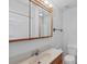 Bright bathroom featuring a sink with wood cabinets, framed mirror, and a white toilet at 11869 Newgate Ave, Port Charlotte, FL 33981