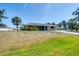 Inviting single-story home with a lush front lawn, mature palm trees, and a welcoming facade at 11869 Newgate Ave, Port Charlotte, FL 33981