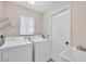 Bright laundry room featuring a washer, dryer, utility sink, and storage shelf at 119 Fairway Rd, Rotonda West, FL 33947