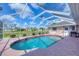 Beautiful screened-in pool area featuring a clear blue pool, red brick trim, and lovely backyard scenery at 119 Fairway Rd, Rotonda West, FL 33947