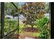 A lovely backyard featuring a tree, green bushes, and grass viewed from a screened patio at 1318 Ballota Ln, North Port, FL 34289