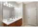 Bright bathroom featuring a double vanity with white countertops, wooden cabinets, and modern lighting fixtures at 1318 Ballota Ln, North Port, FL 34289