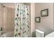 Bathroom with a floral shower curtain, shower head and tile, and a toilet at 1318 Ballota Ln, North Port, FL 34289