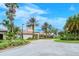Clubhouse entrance with mature palm trees, lush landscaping, and covered portico at 1318 Ballota Ln, North Port, FL 34289