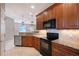 Kitchen with stainless steel dishwasher, granite counters, wood cabinets, and black appliances at 1318 Ballota Ln, North Port, FL 34289