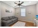 Cozy living room showcasing a comfortable gray sofa, ceiling fan, and natural light from the window at 1318 Ballota Ln, North Port, FL 34289