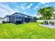 Lush backyard featuring a screened-in pool, covered patio, well-maintained lawn, and privacy fence at 13348 Boabadilla Ln, Port Charlotte, FL 33981