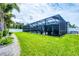 Spacious backyard with screened-in pool, covered patio, lush lawn, and privacy fence at 13348 Boabadilla Ln, Port Charlotte, FL 33981
