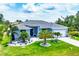 Charming light blue home featuring a gray roof and manicured lawn with decorative palm trees at 13348 Boabadilla Ln, Port Charlotte, FL 33981