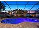 Stunning pool area with a screened enclosure, custom lighting, and lush landscaping at 13348 Boabadilla Ln, Port Charlotte, FL 33981