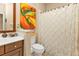 Well-lit bathroom with wood vanity, colorful painting, and patterned shower curtain at 1339 Backspin Dr, Englewood, FL 34223