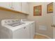 Bright laundry room featuring a white washer and dryer and storage cabinets at 1339 Backspin Dr, Englewood, FL 34223