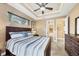 Well-lit bedroom with dark furniture, ceiling fan, tray ceilings, and access to the Primary bathroom at 15092 Chinook Way, Port Charlotte, FL 33981