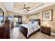 Well-lit bedroom with dark furniture, ceiling fan, tray ceilings, and sliders to outdoor patio at 15092 Chinook Way, Port Charlotte, FL 33981