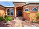 Inviting front entrance with an arched doorway, decorative windows, and lush landscaping at 15092 Chinook Way, Port Charlotte, FL 33981