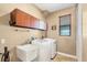 Well-lit laundry room with storage cabinets, utility sink, modern washer and dryer and a window at 15092 Chinook Way, Port Charlotte, FL 33981