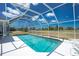 A screened-in pool with crystal clear blue water and white deck and chairs is set against a bright blue sky at 162 Fairway Rd, Rotonda West, FL 33947