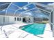 A screened-in pool is set against a white house with lawn furniture with an outdoor table set for dining at 162 Fairway Rd, Rotonda West, FL 33947