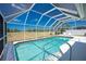 A screened-in pool with clear blue water, surrounded by a white deck and a view of a grassy field at 162 Fairway Rd, Rotonda West, FL 33947