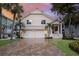 Inviting two-story home with a paved driveway, two-car garage, and manicured lawn with tropical landscaping at 16716 Grande Quay Dr, Boca Grande, FL 33921