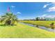 Waterfront backyard featuring lush grass and a picturesque canal view under a sunny sky at 169 Fairway Rd, Rotonda West, FL 33947
