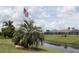 Picturesque backyard view with American flag, canal, mature palms, and neighboring screened lanais at 169 Fairway Rd, Rotonda West, FL 33947