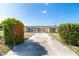 Charming single-story home featuring a long driveway, lush landscaping and a welcoming facade under a clear blue sky at 2075 Georgia Ave, Englewood, FL 34224
