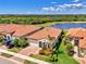 Aerial view showcases a home with a red tile roof and lush landscaping, located next to a picturesque lake at 23590 Copperleaf Dr, Venice, FL 34293