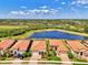 Scenic aerial view showcasing a neighborhood with red tile roofs and a serene lake surrounded by lush greenery at 23590 Copperleaf Dr, Venice, FL 34293