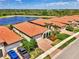 Overhead view captures several homes with red tile roofs, surrounded by lush landscaping and serene lake views at 23590 Copperleaf Dr, Venice, FL 34293